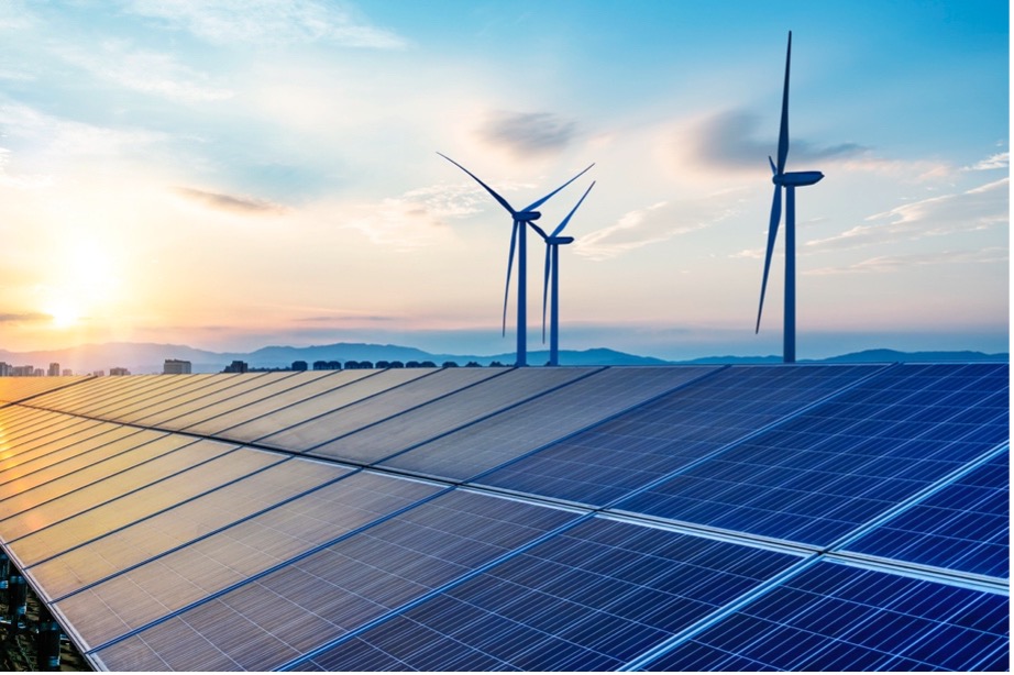 Solar panels and wind turbines in front of a sunset