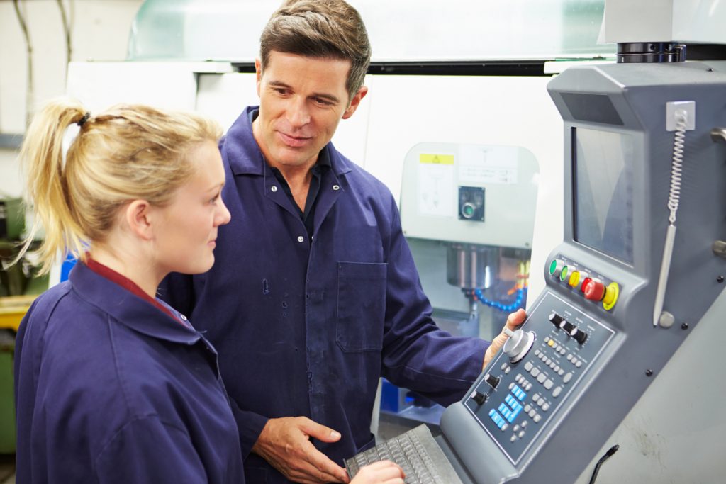 Trained Engineer And Apprentice Using Automated Milling Machine Together