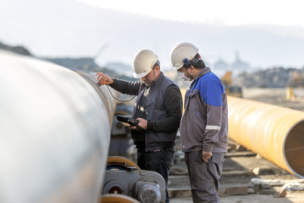 Non-destructive testing technicians are checking welds of pipe with ultrasonic testing (UT) method. Ultrasonic testing is often performed on steel and other metals and alloys.