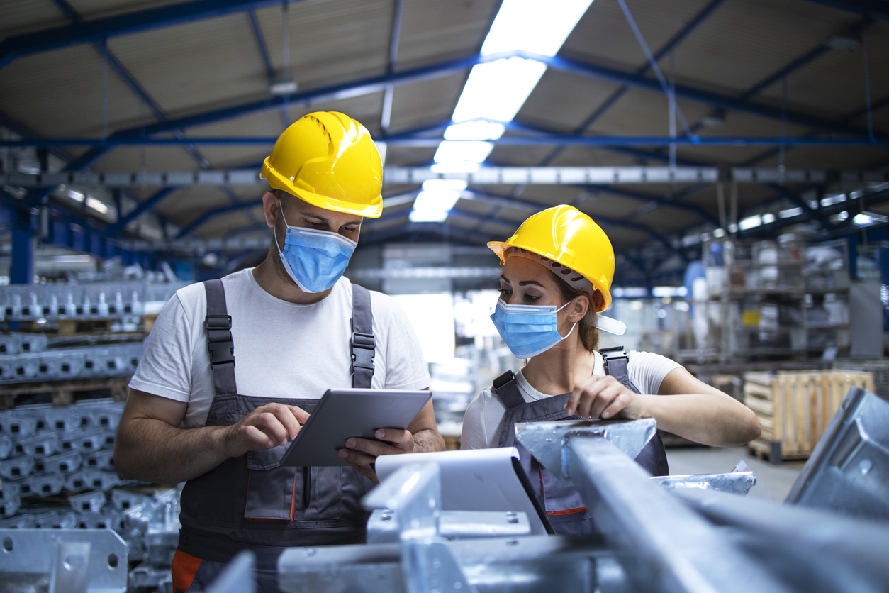 Industrial workers with face masks and yellow helmets