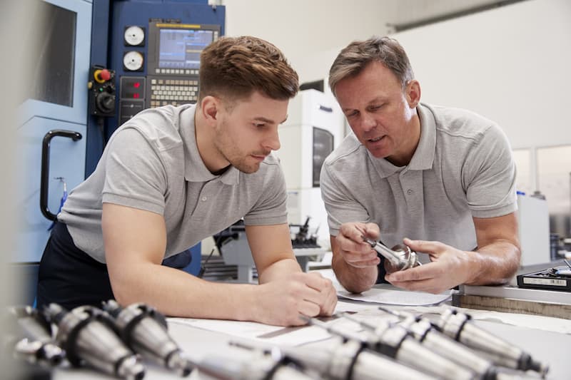male engineering apprentice learning from colleague