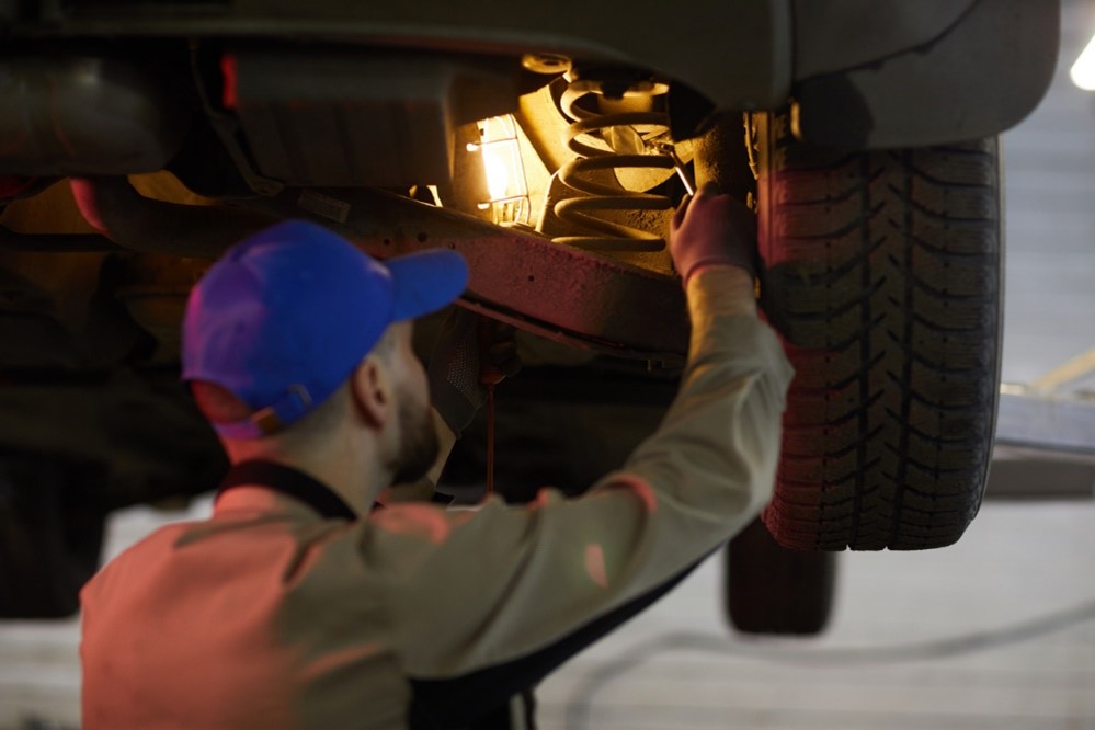 Manufacturing engineer installing suspension springs on cars