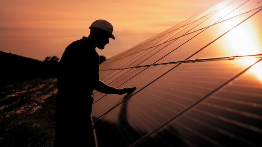 A person in a hard hat touching a solar panel