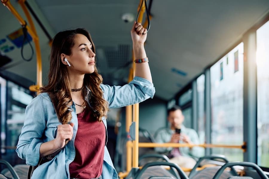 A person standing on a bus holding her hand up