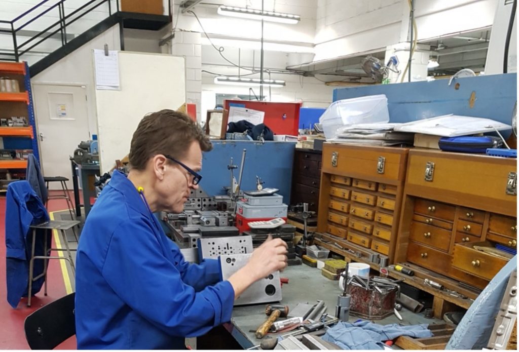 A person in a blue uniform working on a machine